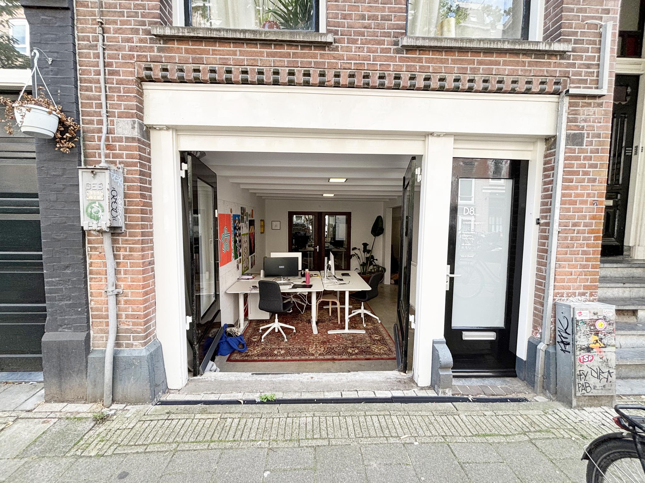 Ingekijk in een open kantoorruimte aan de Van Ostadestraat met bureaus, computers en kleurrijke posters aan de muur.